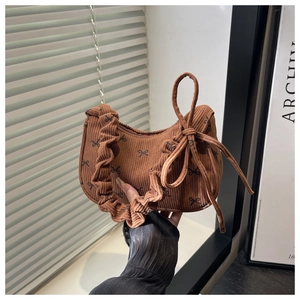 Détail du sac en velours côtelé marron avec motifs nœuds et poignée à volants