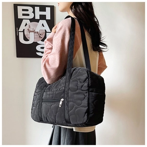 Detail of black heart-quilted large travel bag showing shoulder strap and side view
