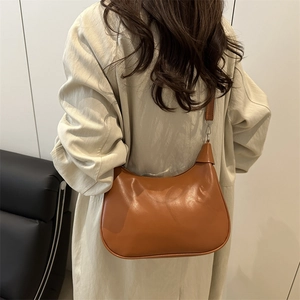 Chic brown crescent leather shoulder bag for women styled in a minimalist interior setting