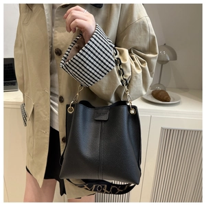 Detail of black lychee grain bucket bag with metal chain and geometric print strap