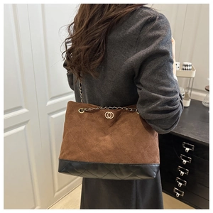 Detail of brown suede and black leather patchwork bag with classic quilted stitching