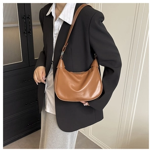 Detail of caramel half-moon hobo bag with smooth leather texture and metallic logo
