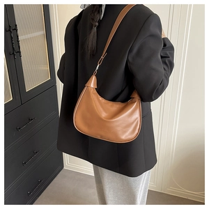 Detail view of a brown leather half-moon hobo bag with a silver buckle and minimal logo