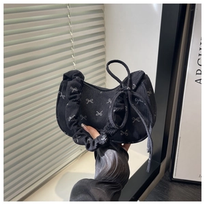 Détail de texture du sac hobo en velours côtelé noir avec motifs de nœuds blancs