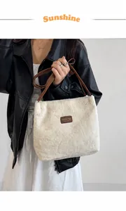 Détail du sac fourre-tout en peluche montrant la texture beige et les anses en cuir brun