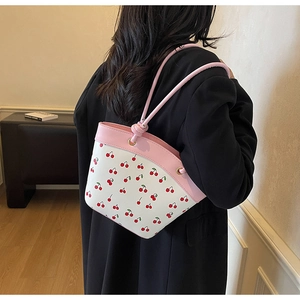 Detail of pink and white cherry print handbag with knotted leather strap on shoulder