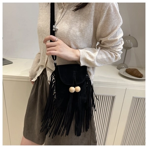 Détail d'un sac bandoulière noir en daim avec de longues franges et perles en bois