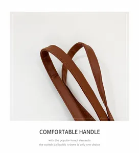 Détail des poignées en similicuir marron avec coutures contrastées jaunes sur le sac cabas