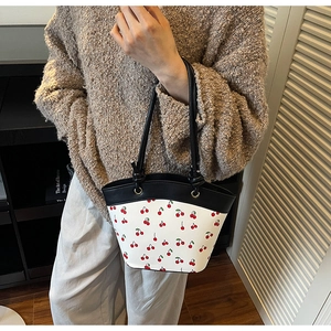 Close-up of red cherry print on contrast color tote bag with black slim handles