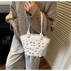 Detail showing the white cherry print bucket bag with knots and metallic eyelets