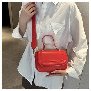 Detail of red leather crossbody bag with wide shoulder strap and flap stitching design