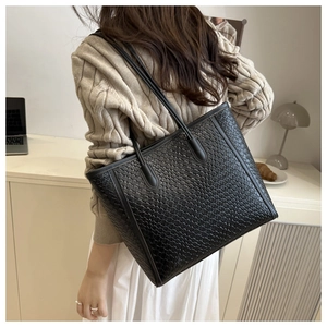 Detail showing woven texture and slender strap of this black leather tote bag