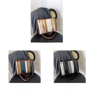Detailed comparison of striped tote bags in beige, blue, and black with metal chains