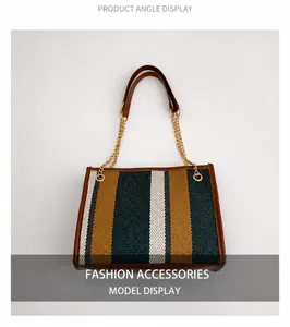 Detail of colorful striped canvas tote bag with brown leather trim and golden metal chain