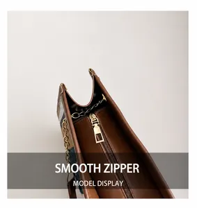 Detail of smooth gold zipper on vintage tote bag with plaid fabric and brown leather edges