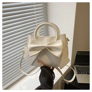 Detail of off-white handbag featuring a large bow knot and textured matte synthetic leather