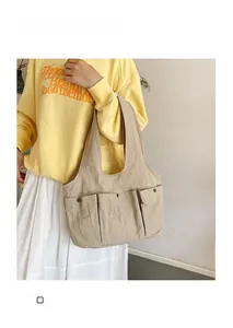 Detail showing three small front pockets with snap buttons on a beige nylon tote bag