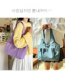 Detail of large nylon tote bag with pleated texture and exterior pocket button in purple and blue
