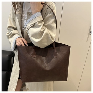 Close-up of dark brown tote bag showing reinforced stitching and matte leather texture