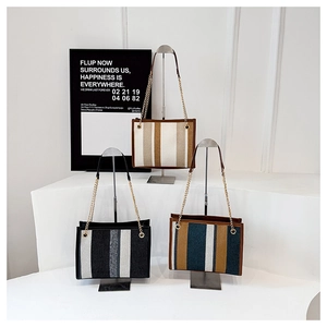 Three striped canvas tote bags in various colors hanging on a silver metal display rack