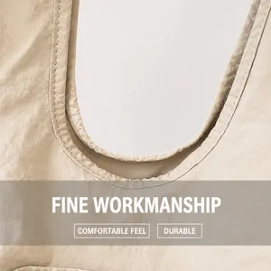 Detailed close-up of U-shaped stitching on beige pleated tote bag with reinforced handles
