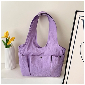 Detail of purple pleated tote bag with three large pockets and black metal snap closure