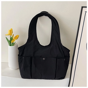 Detail of minimalist black multi-pocket tote bag with vintage metal button and tulips