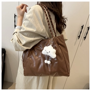 Detailed view of dark brown tote bag featuring diamond quilting and plush cloud charm