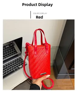 Detailed view of red woven texture and metal logo plaque on a mini crossbody bag
