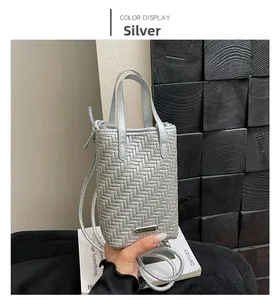 Close-up of silver woven texture crossbody bag with metal logo and thin shoulder strap
