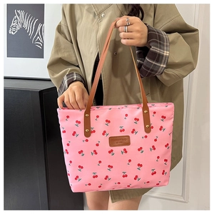 Detail of pink cherry print tote bag with brown leather straps and metal rivets