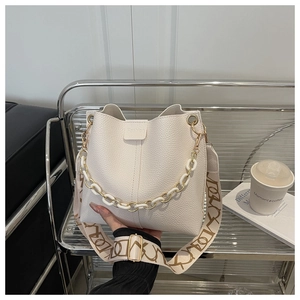 Detail of off-white bucket bag with lychee leather texture and patterned strap