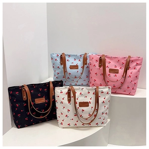 Group display of cherry print tote bags in black, blue, pink, and white on pedestals