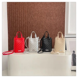 Gros plan de quatre mini sacs bandoulière tissés en rouge, argent, noir et blanc cassé