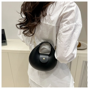 Détail d'un sac demi-lune noir mat avec boucle dorée et bandoulière en chaîne fine