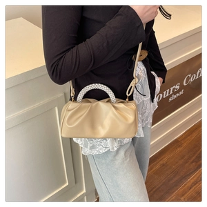 Detail of off-white ruched cloud bag featuring elegant woven pearl handle for women