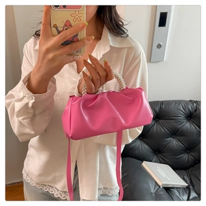 Detail of bright pink ruched cloud bag featuring pearl handle and glossy PU texture