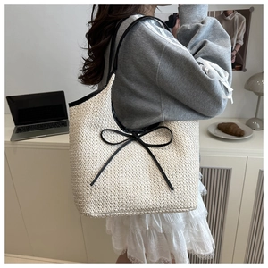 Detail of hand-woven tote bag with black bow decoration and contrasting trim