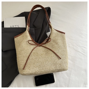 Detail of woven straw tote bag with brown leather trim and delicate bow knot decoration