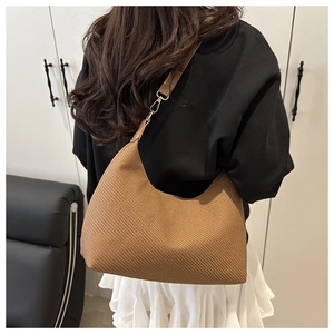 Detail of brown woven hobo bag showing texture, crescent shape and gold metal buckle