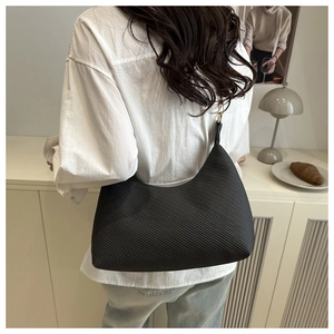 Detailed back view of a black knitted crescent shoulder bag with twill texture on a model