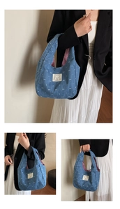 Detail einer blauen Denim-Einkaufstasche mit weißen Schleifen und Bären-Aufnäher