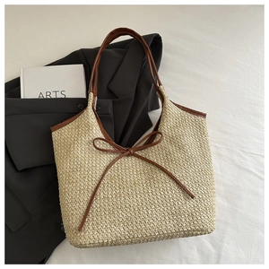Détail d'un sac cabas en paille tressée avec anses en cuir marron et un nœud élégant