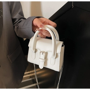 Detail der weißen Mini-Lederhandtasche mit silberner Schnalle und abnehmbarer Kette