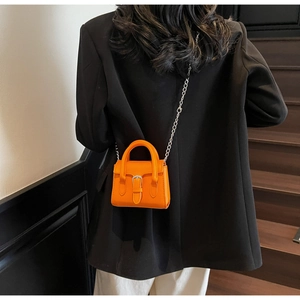 Detailed back view of mini orange crossbody bag with silver buckle and metallic chain strap