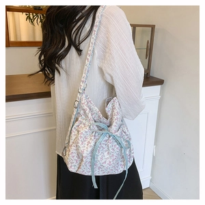Detailansicht der Leinwand-Eimertasche mit Blumenmuster, Karo-Schleife und Metallring-Dekor
