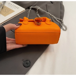 Detailed close-up of vibrant orange mini bag showing fine stitching and silver chain strap