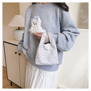 Détail d'un sac cabas floral en toile assorti à un sweat gris avec motif de chien