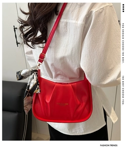 Dettaglio della borsa a tracolla rossa in pelle pieghettata con foulard di seta decorativo
