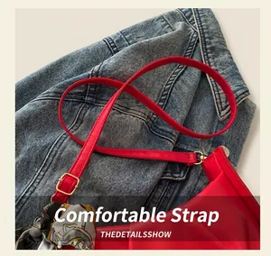 Détail d'un sac en cuir plissé rouge avec bandoulière à boucle dorée et foulard en soie